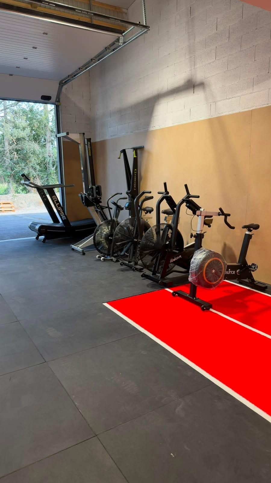 Espace cardio : tapis de course, rameur et vélos le long du mur